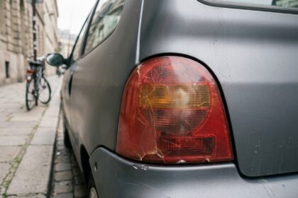 Feu arrière fissuré et jauni sur une petite voiture urbaine grise garée en ville