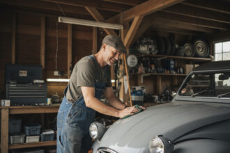 Homme en salopette polissant une Citroen 2CV dans son garage