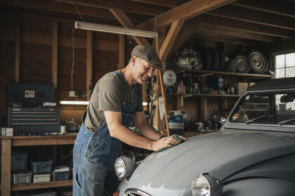 Homme en salopette polissant une Citroen 2CV dans son garage
