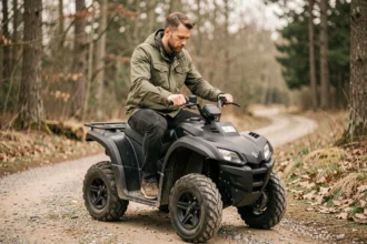 Homme adulte sur un quad électrique entrée de gamme en forêt, vue 3/4