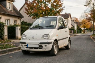 Voiture sans permis d'occasion compacte garée dans une rue résidentielle française, modèle type Aixam ou Ligier légèrement usé
